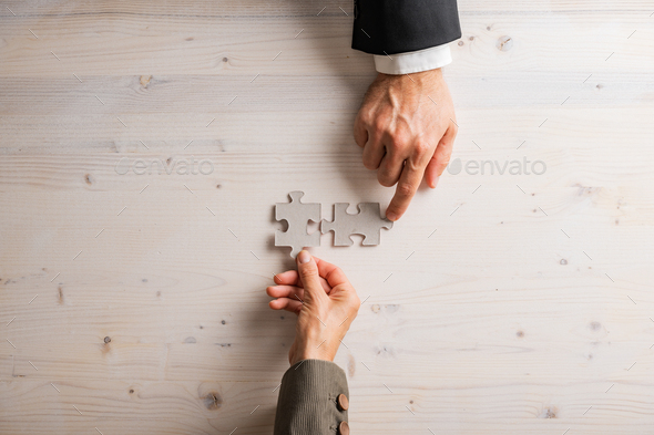 Male and female hand joining two blank matching puzzle pieces - Stock Photo - Images