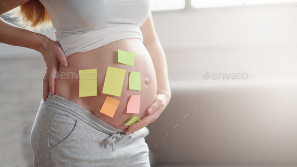 Concept of choosing baby name. cropped shot of pregnant woman with question marks on paper stickers - Stock Photo - Images