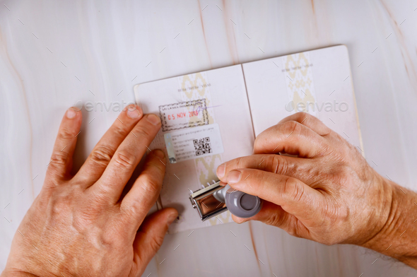 Border control officer puts a stamp in the passport page of passport stamps. Immigration Service