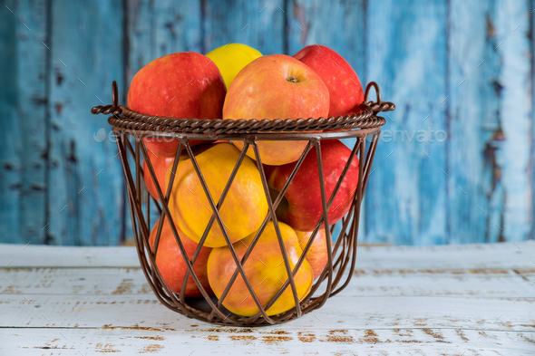 Fruit steel basket with red, orange apples.