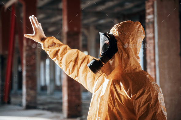 Man dressed in chemical protection suit in the ruins of the post apocalyptic building