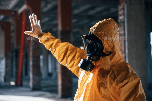 Man dressed in chemical protection suit in the ruins of the post apocalyptic building