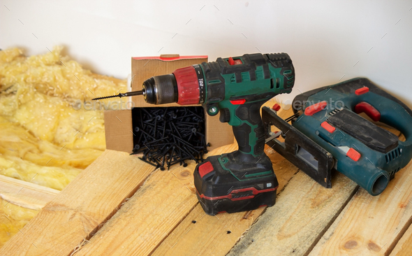 A man makes repairs in the house, a screwdriver, screws, a saw.