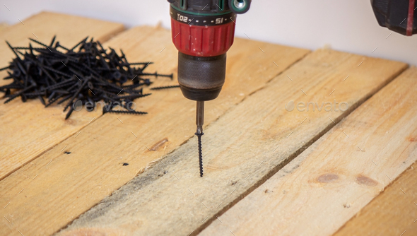 A man makes repairs in the house, a screwdriver, screws, a saw.