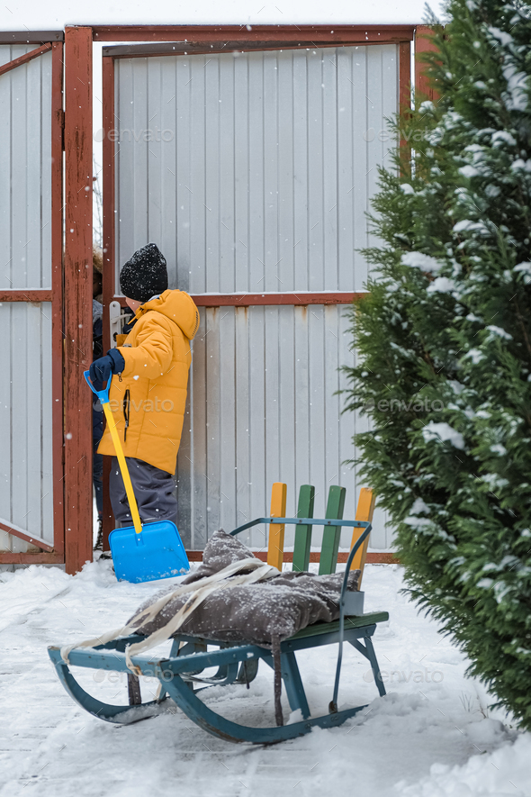 Close-up of a children cleaning and clearing snow in front of the house on a sunny and frosty day. C - Stock Photo - Images