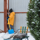 Close-up of a children cleaning and clearing snow in front of the house on a sunny and frosty day. C - PhotoDune Item for Sale