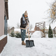 Close-up of a woman cleaning and clearing snow in front of the house on a sunny and frosty day. Clea - PhotoDune Item for Sale