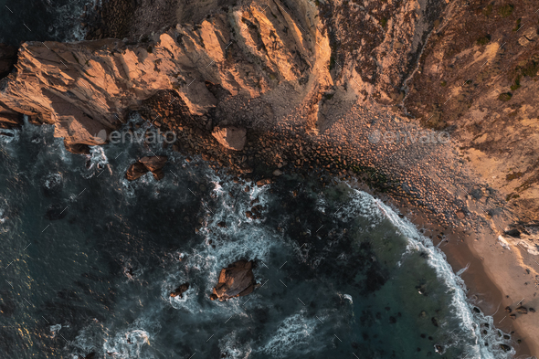 Aerial view of rocky cliff on seacoast with waves