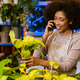 Young florist girl talking on cellphone while working in flower shop - PhotoDune Item for Sale