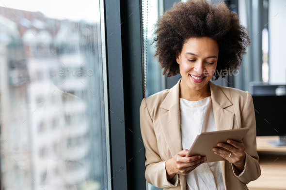 Portrait of a smiling confident african american young businesswoman working with digital tablet - Stock Photo - Images