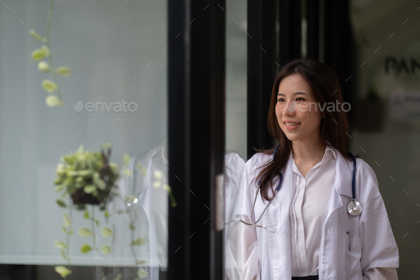 Portrait happy asian woman doctor looking outside in hospital - Stock Photo - Images