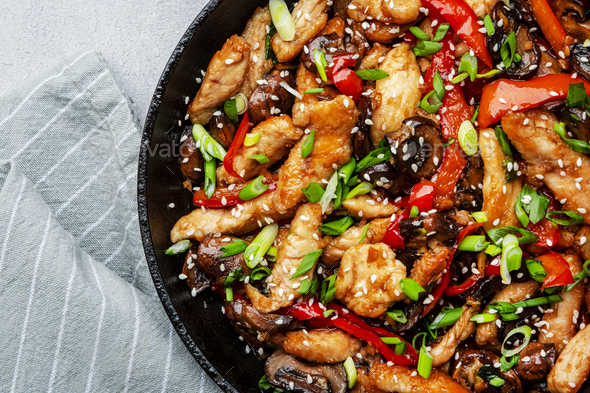 Stir fry with chicken, red paprika, mushrooms and chives in frying pan ...