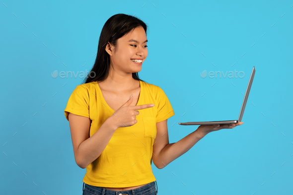 Ad and offer, huge sale. Happy young asian lady student in yellow t-shirt point finger at computer