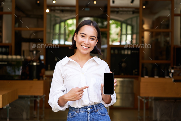 Happy asian woman, cafe manager standing in front of restaurant ...