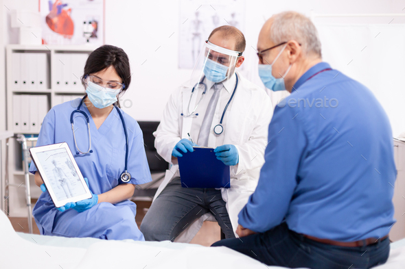 Doctor discussing about bone disease with senior man pointing at tablet pc