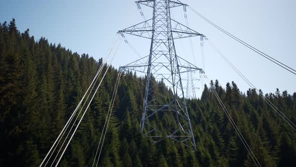 Aerial view of high voltage electricity pylons in a dense mountain forest. 4k alt