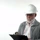A Bearded Elderly Pensioner Man in a Construction Helmet Writes Annotations with a Pen on a Writing - VideoHive Item for Sale