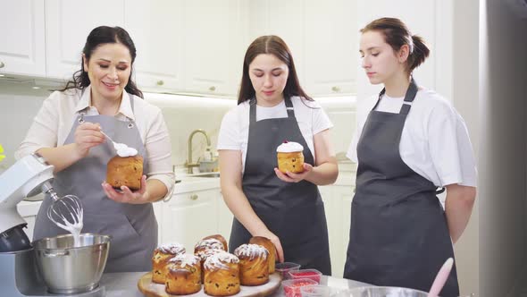 a Mother and Daughters Decorate Icing Dried Berries and Flowers Easter Cakes alt