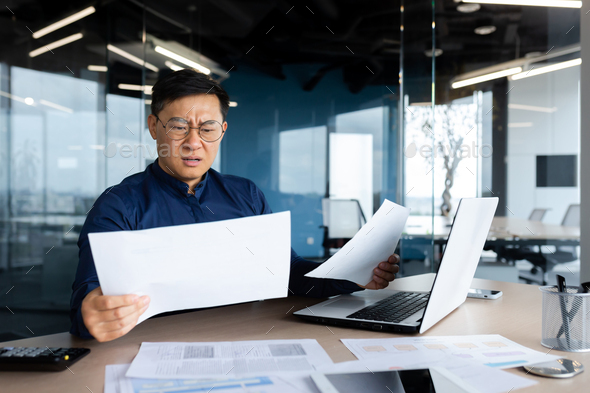 Asian businessman not satisfied with achievement results, boss looking at documents and upset, man