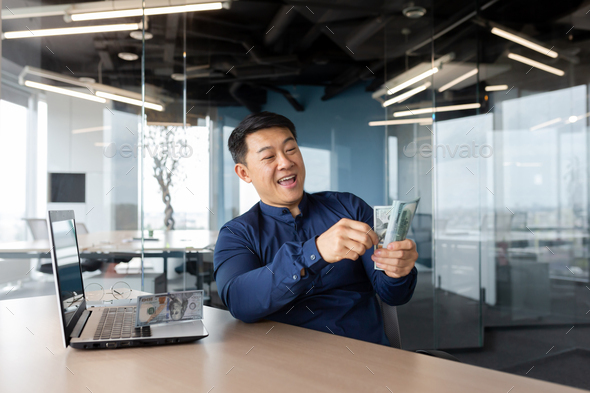 Happy and successful businessman counting money cash inside office, investor satisfied with