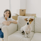 Happy woman plays with favourite pet, poses near sofa in new apartment, celebrate Moving Day - PhotoDune Item for Sale