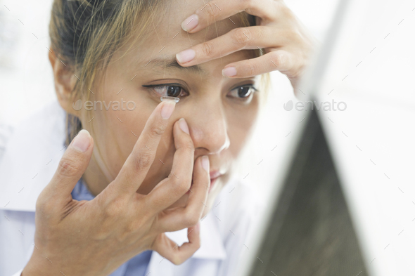 Close up of woman putting contact lens in her eyes. - Stock Photo - Images