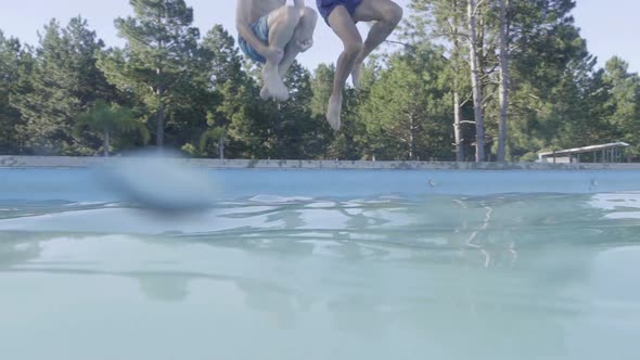 Man and boy jumping into swimming pool together