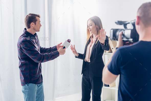 beautiful businesswoman in suit rejecting giving interview to journalist and showing stop sing to