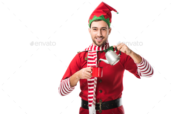 happy man in christmas elf costume with metal kettle pouring tea in cup and looking at camera
