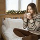 Caucasian young woman sitting on bed with cup of coffee and looking away - PhotoDune Item for Sale
