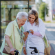 Portrait of caregiver with senior woman on walk in park with shopping bag, laughing and talking. - PhotoDune Item for Sale