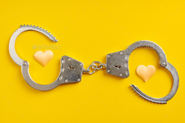 Opened handcuffs on yellow background. Stock Photo by travelarium