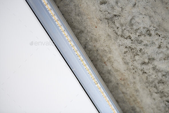 Strip LED light with aluminum profile on stretch ceiling, close up. Home renovation concept