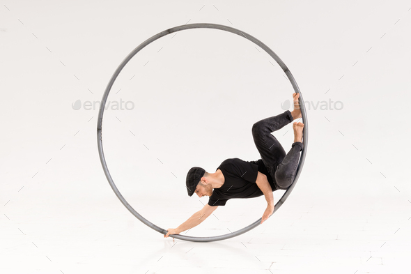 Male acrobat performing trick in hoop - Stock Photo - Images