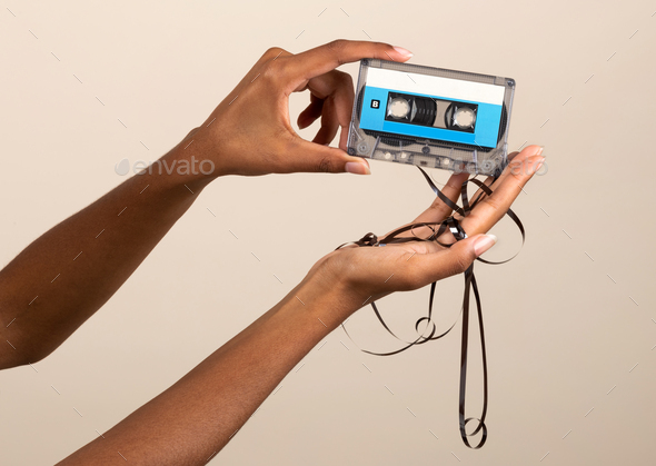 Faceless female showing retro cassette tape - Stock Photo - Images