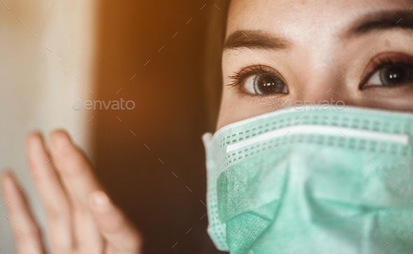 Woman wearing mask protection at the window wait for epidemic situation to improve soon at home.