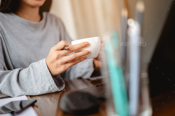 Woman holding a coffee cup work from home wait epidemic situation to improve soon at home.