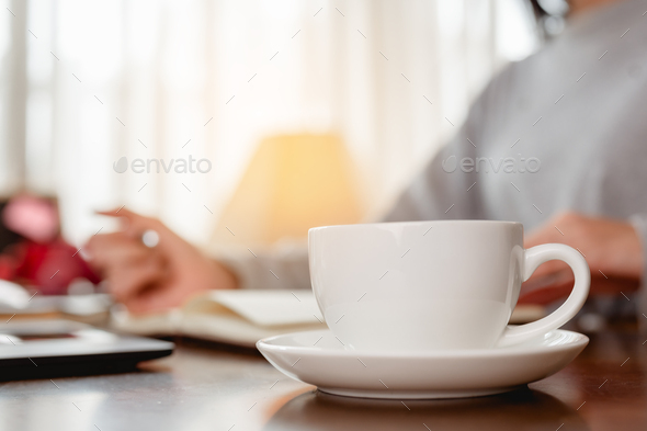 Woman work from home have a coffee cup beside wait epidemic situation to improve soon at home.