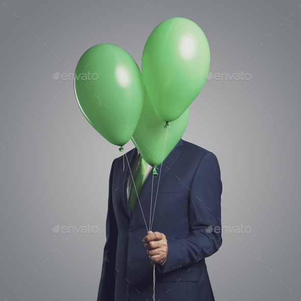 Businessman hiding behind balloons - Stock Photo - Images