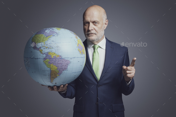 Businessman holding a globe and pointing - Stock Photo - Images