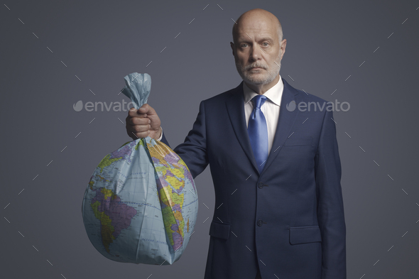 Businessman holding a polluted earth shaped as trash bag - Stock Photo - Images