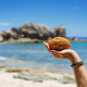 Man holding fresh peeled coconut fruit on exotic tropical white sand beach on sunny day - PhotoDune Item for Sale