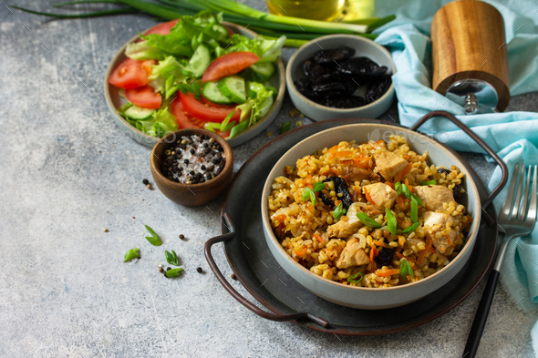 Bulgur with chicken, vegetables and prunes on a gray stone or slate countertop. Copy space. - Stock Photo - Images