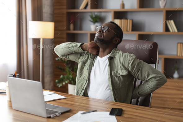 Unhappy despair middle aged african american businessman in glasses suffering from back pain at