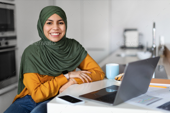 Freelance. Middle Eastern Woman In Hijab Sitting At Desk With With Laptop - Stock Photo - Images