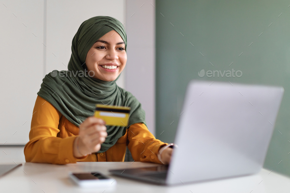 Online Payments. Smiling Muslim Woman In Hijab Using Laptop And Credit Card - Stock Photo - Images