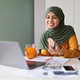 Young Muslim Woman Eating Snacks In Front Of Laptop At Home - PhotoDune Item for Sale