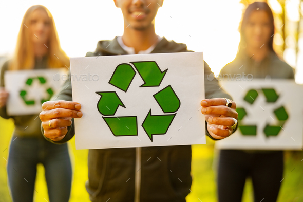 Man holding placard with recycling symbol with his enviromental team at park - Stock Photo - Images