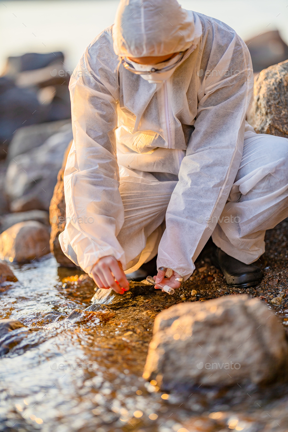 Close-up of researcher collecting water sample at seashore - Stock Photo - Images