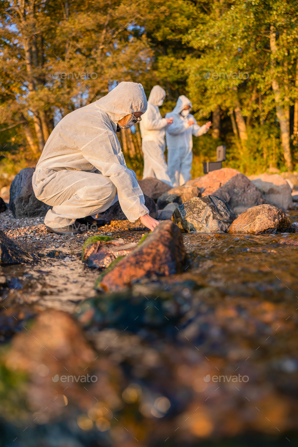 Team of researchers analyzing water sample at seashore - Stock Photo - Images